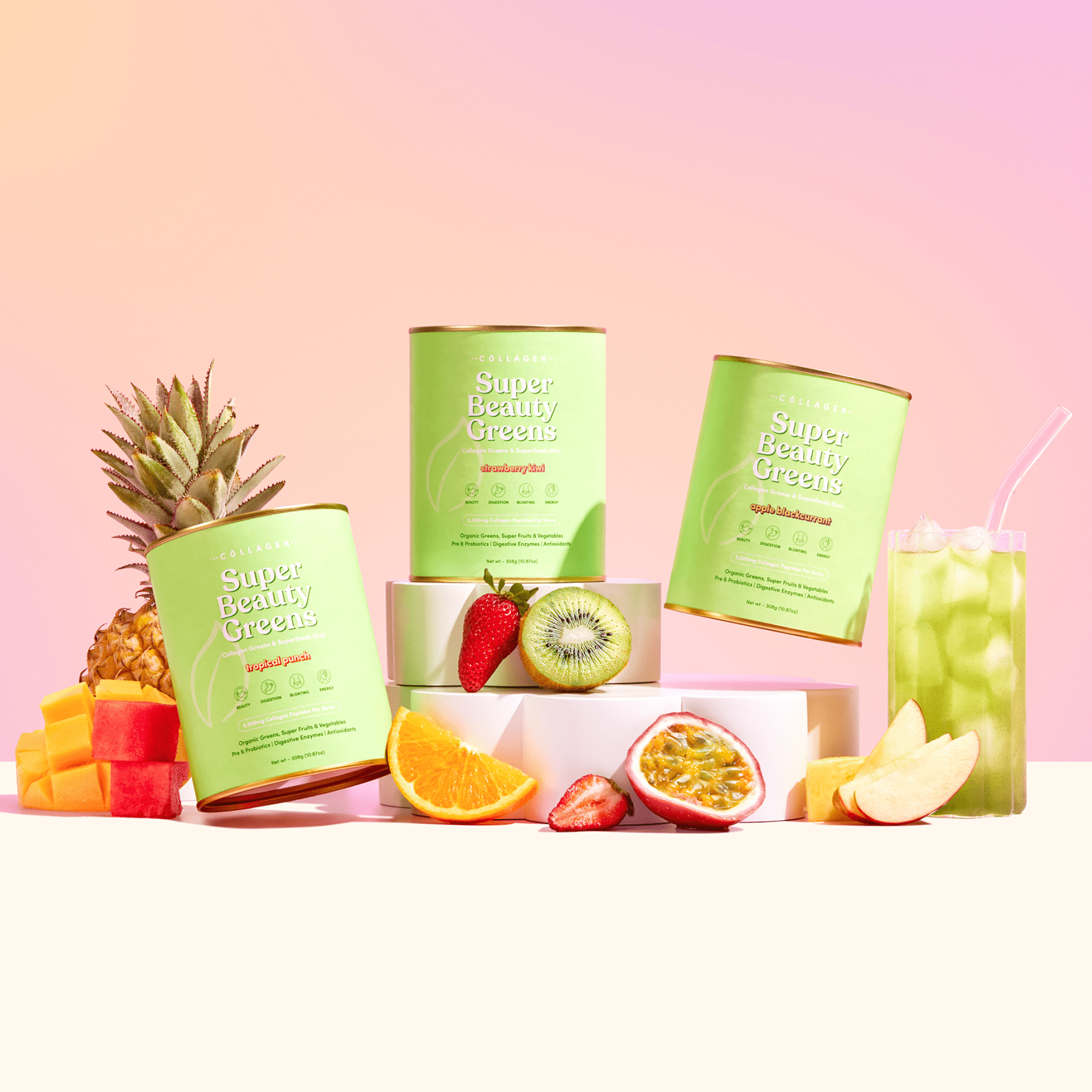 Three green Super Beauty Greens collagen containers surrounded by pineapple, strawberries, kiwi, orange, passion fruit, and a green beverage.