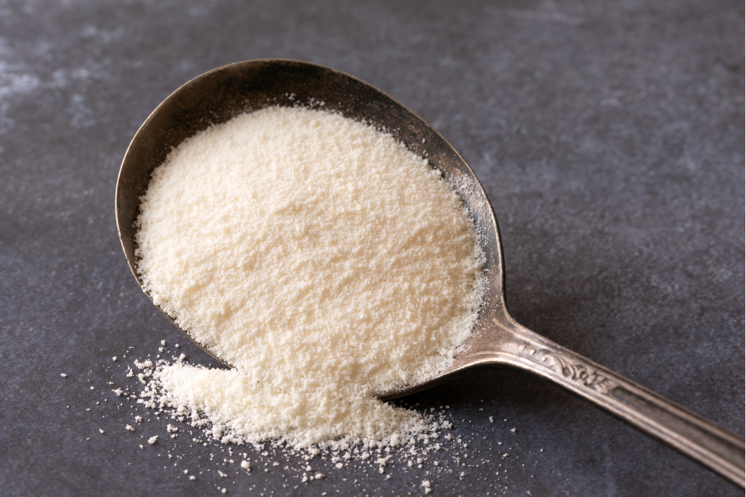A vintage spoon filled with fine collagen powder on a dark surface, highlighting beauty supplements and skincare benefits.