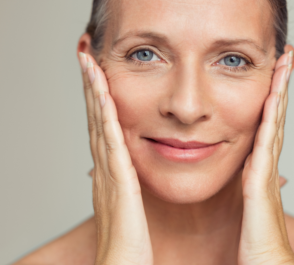 Smiling woman touching face, showcasing healthy, radiant skin. Ideal for beauty and skincare focus, highlighting age-defying supplements.