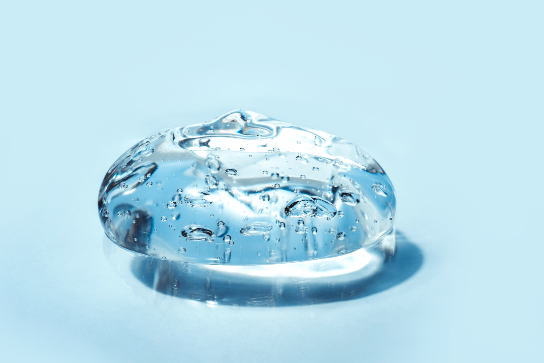 Clear gel blob with air bubbles on a light blue background, resembling a skincare product or collagen supplement.