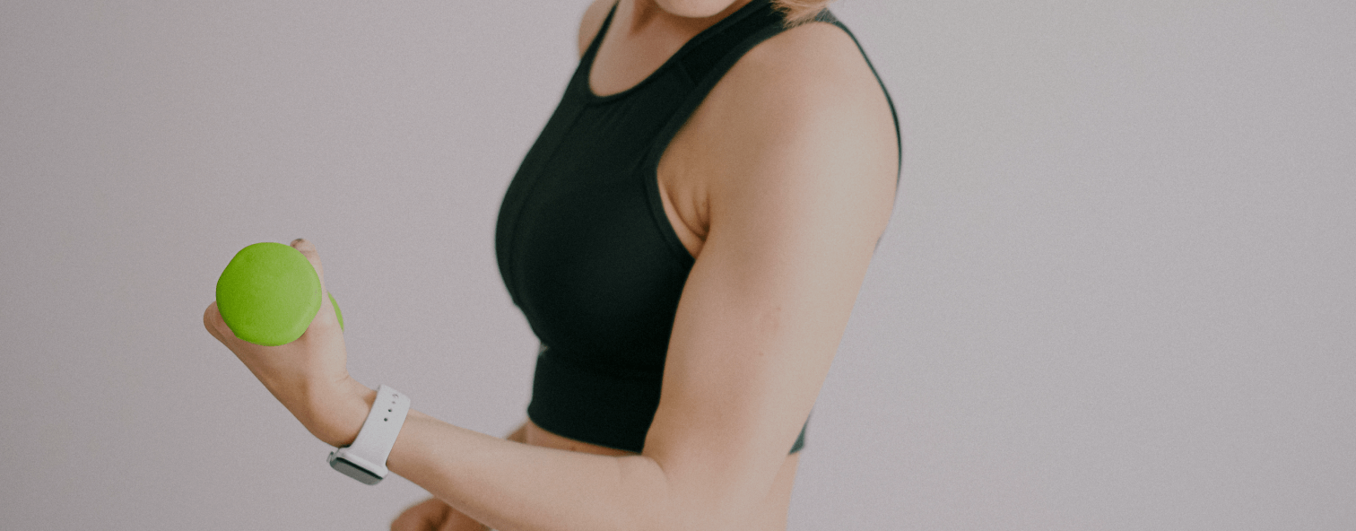 Woman in black sports bra holding a green ball, with a white fitness tracker on her wrist, suggesting a focus on health and beauty.