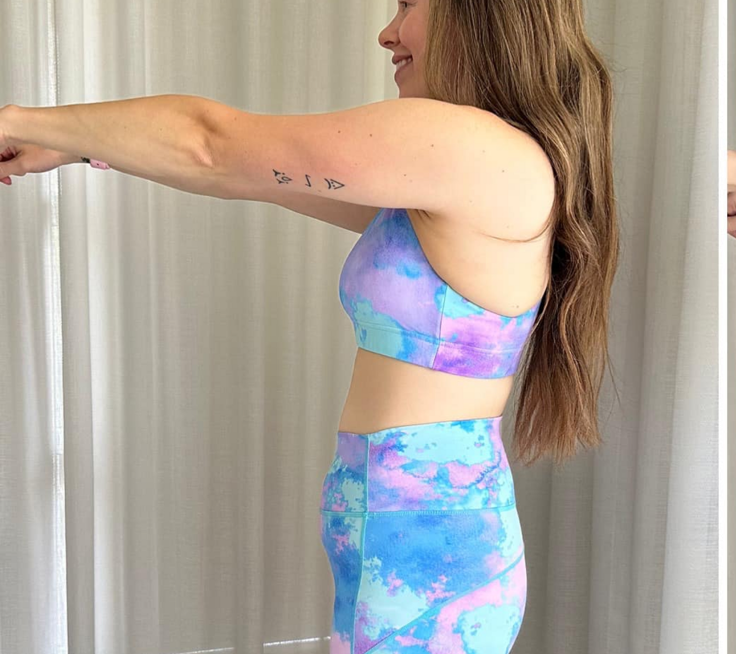 Woman in colorful yoga outfit stretching arms forward.