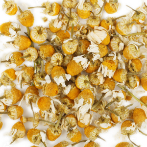Dried chamomile flowers scattered on a white background, ideal for natural beauty supplements and calming teas.