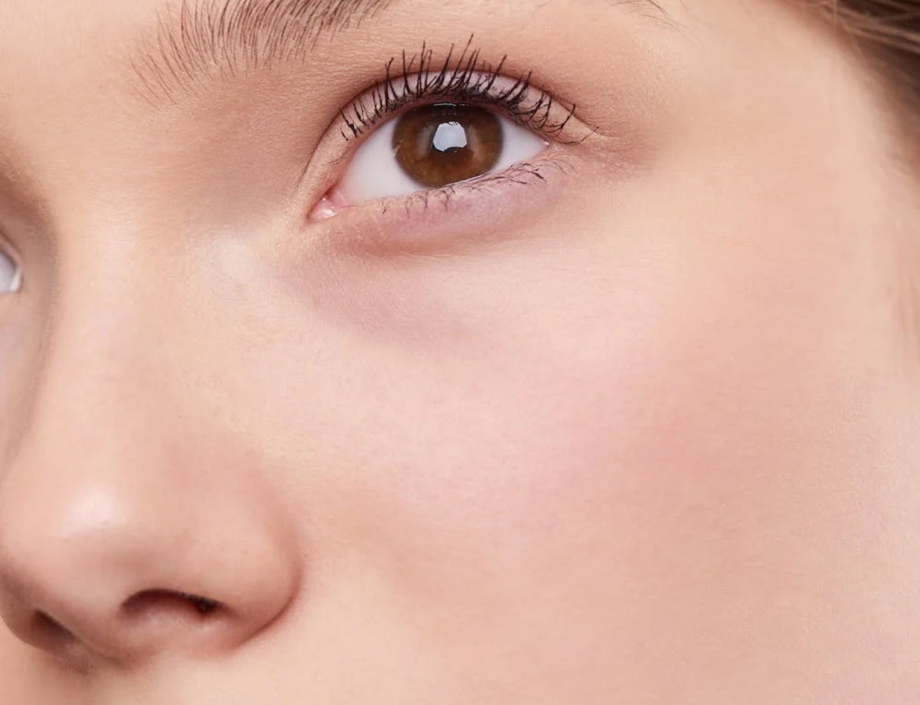 Close-up of a woman's eye and cheek, highlighting smooth skin and beauty.