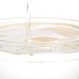 Clear liquid pouring into a glass dish, likely collagen supplement, emphasizing beauty and wellness benefits.