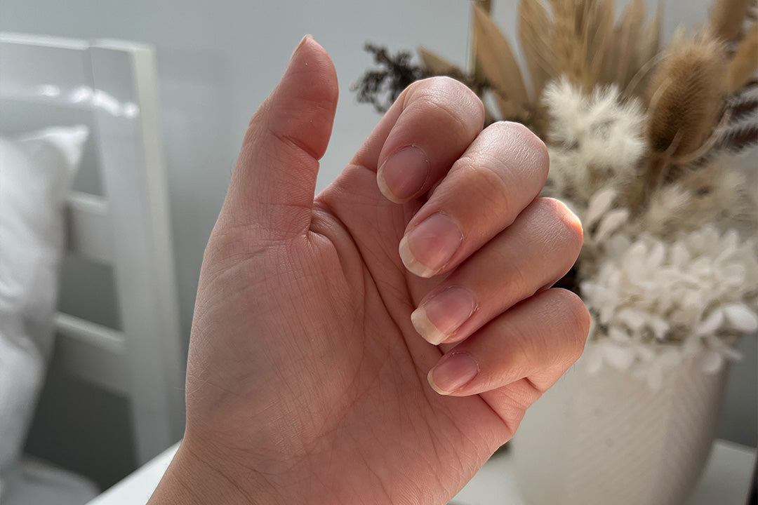 Close-up of a hand displaying healthy, natural nails, with a soft-focus background of dried floral decor. Perfect for beauty and wellness themes.