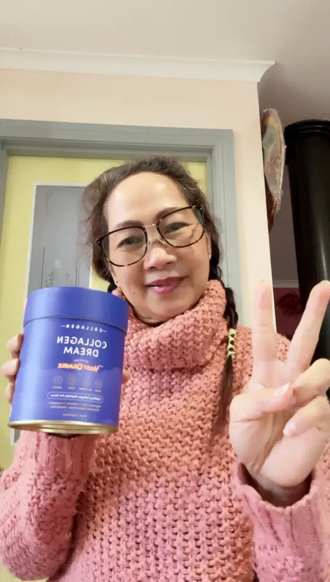 A woman in glasses and a pink sweater smiles while holding a blue container labeled Collagen Dream and making a peace sign with her other hand.