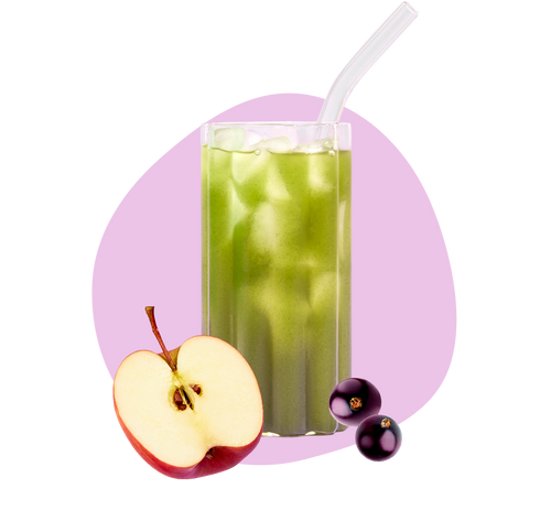 A glass of green juice with ice and a straw, placed in front of a pink shape, with a sliced red apple and two blackcurrants beside the glass.