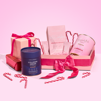 A gift box with a pink ribbon, The Collagen Co. Daily Glow Starter Set, and candy canes are arranged on a pink background. Some products, like the blue canister and the pink and gold container, are placed outside the box.