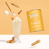 A creamy protein shake topped with whipped cream, churros, a gold spoon of powder, and a yellow canister labeled The Collagen Co. Cinnamon Churro Collagen Meal Replacement - 756g with hydrolyzed collagen peptides.