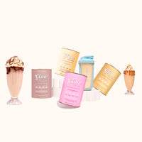 Five pastel-colored cans of Glow Shake Starter Kit by The Collagen Co USA are neatly arranged with a Collagen Protein Shaker, while two milkshakes topped with whipped cream and syrup emphasize the deliciousness of every Glow Shake.
