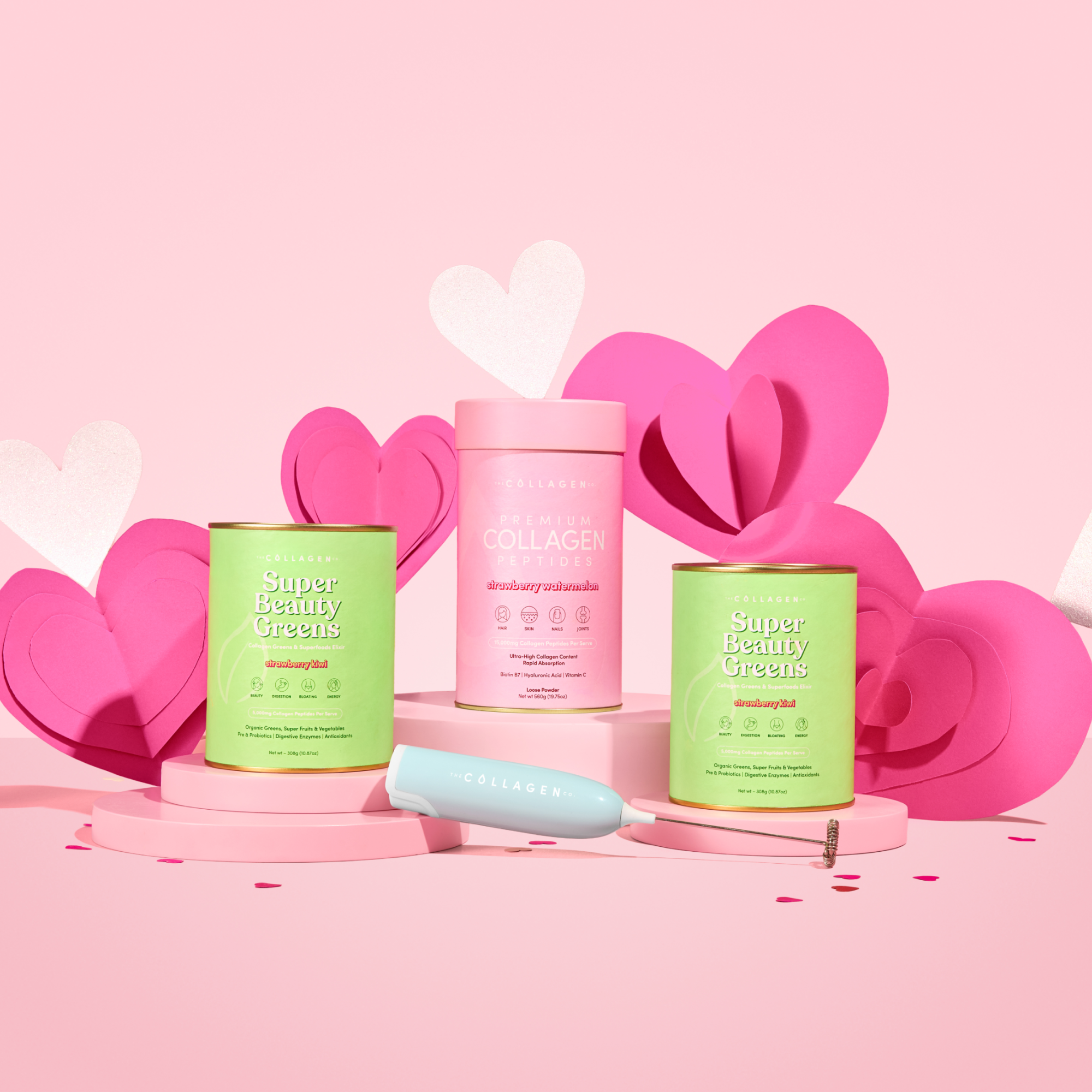 The Collagen Co. Gut Feelings Beauty Bundle, featuring colorful supplement containers and a beauty tool, is displayed on a pink background with playful heart-shaped decorations for a vibrant and fun look.