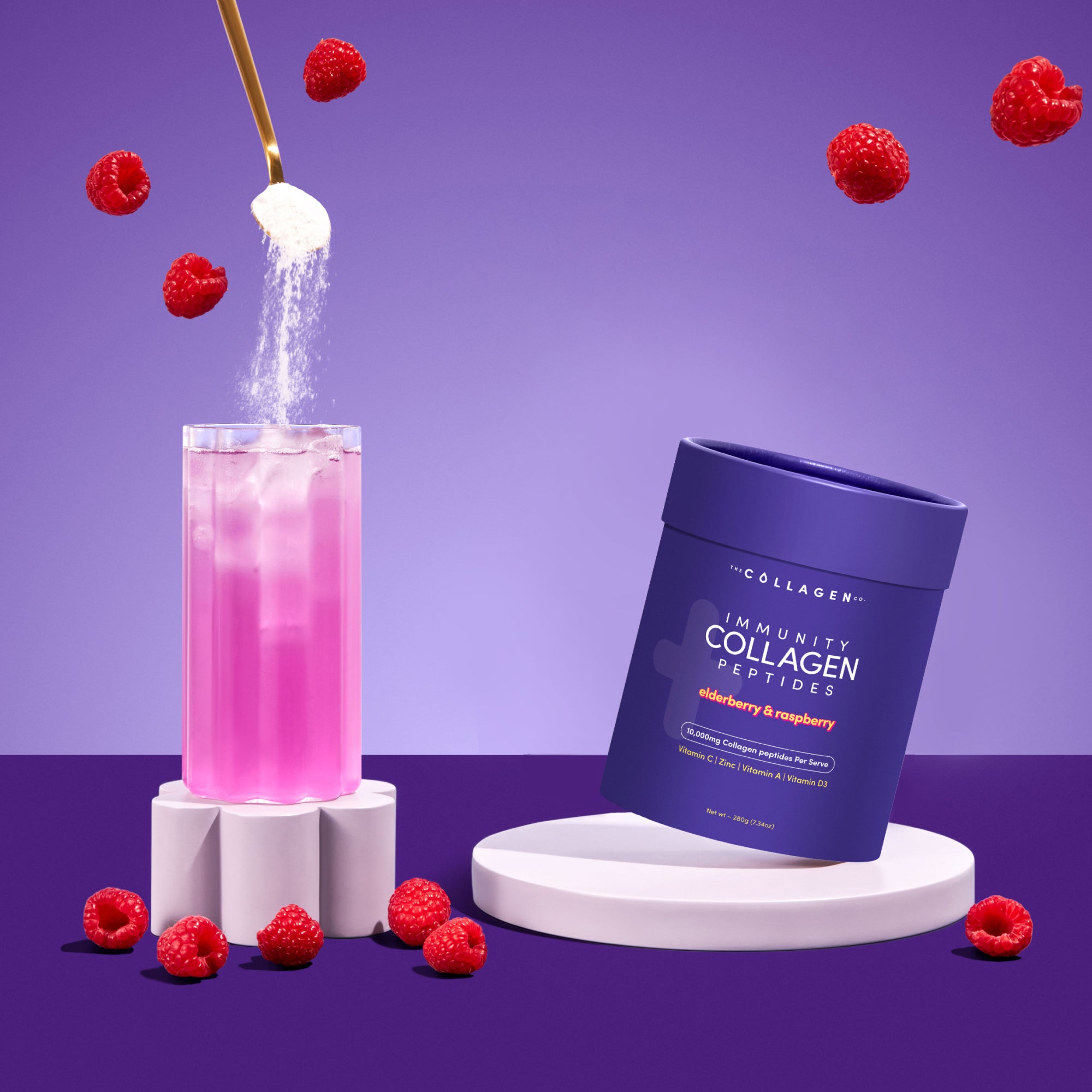 A pink iced drink is topped with Hydrolysed Bovine Collagen Powder as The Collagen Co. Immunity Collagen Peptides - Elderberry & Raspberry 208g sits nearby among raspberries, showcasing its immune-supporting nutrients.