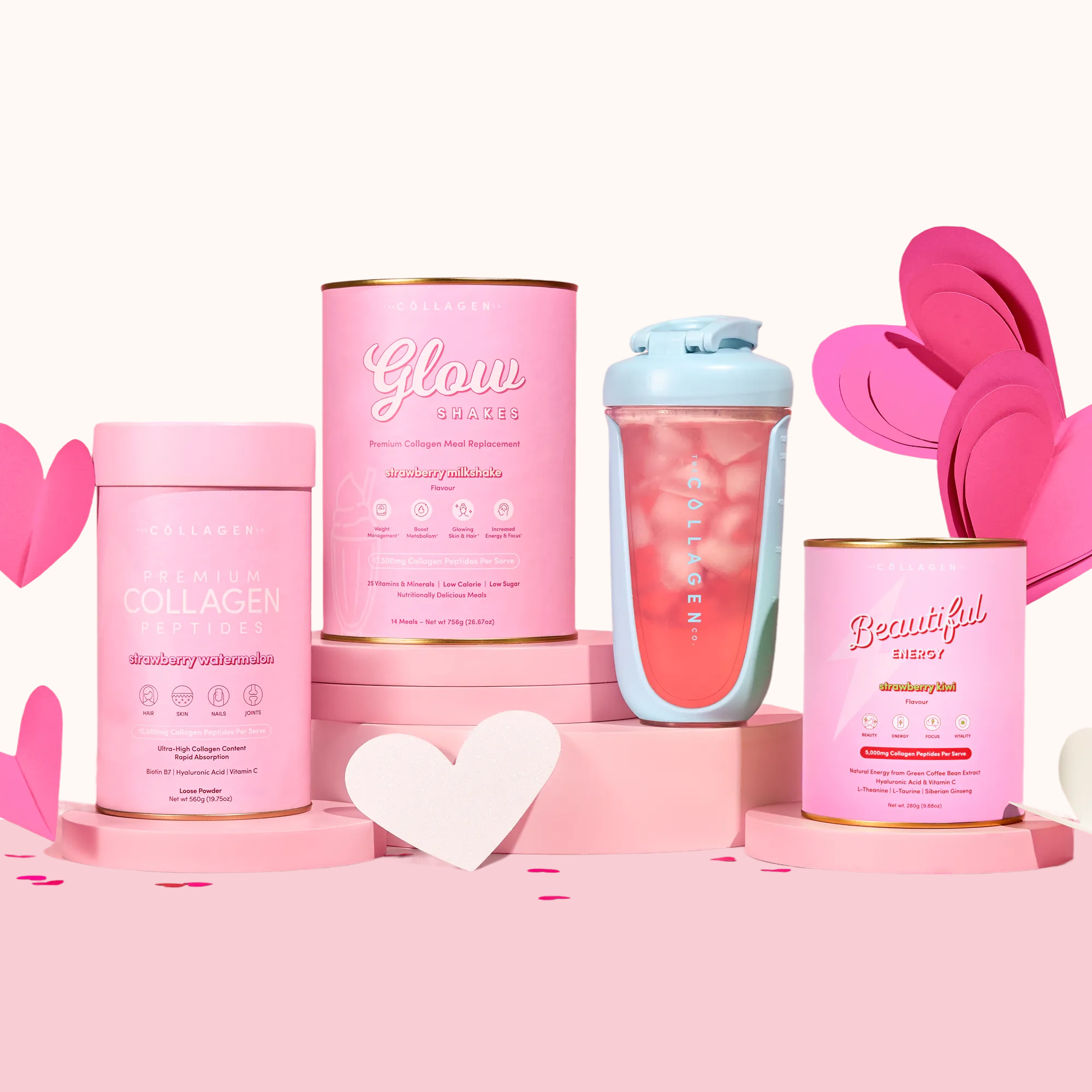 The Collagen Co.’s Love Your Glow Bundle, featuring collagen peptides supplements and a shaker with a pink glow shake, is displayed on pink platforms with heart decorations for a cheerful, vibrant look.