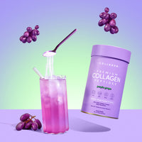 A vibrant purple grape drink with ice and a metal straw sits beside a thecollagen.co Purple Grape Collagen Powder (560g) canister—a beauty supplement featuring hydrolysed bovine collagen peptides. Grapes float on a pastel purple and green gradient background.