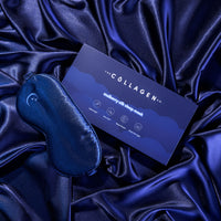 A Mulberry Silk Sleep Mask from The Collagen Co. and its box sit on smooth, dark blue silk. The box highlights that this hypoallergenic mask is lightweight, anti-aging, and gentle on both skin and hair.