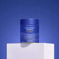A blue container of The Collagen Co. Choc-Honeycomb Collagen Dream Advanced Sleep Formula Hot Chocolate (231g) sits on a white pedestal against a blue background, with white and gold text highlighting its collagen peptide supplement benefits.