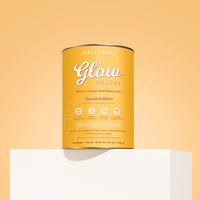A yellow canister of The Collagen Co. Cinnamon Churro Collagen Meal Replacement (756g) sits on a white pedestal against a peach background, offering a protein-rich shake with hydrolyzed collagen peptides for enhanced benefits.