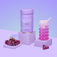 A 560g container of thecollagen.co’s Purple Grape Collagen Powder stands beside a glass of pink iced drink and red grapes, set against a purple gradient background, spotlighting this beauty supplement.