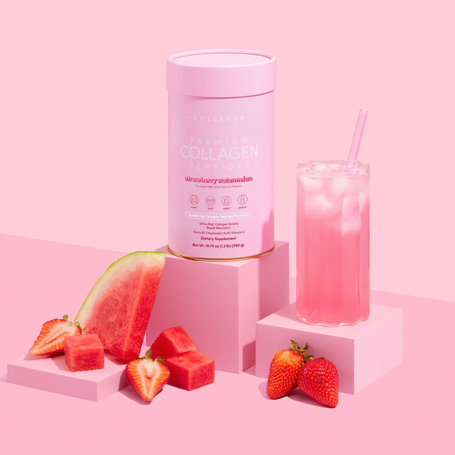 Collagen powder container with a glass of pink drink, watermelon, and strawberries on a pink background
