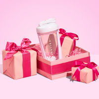 A vibrant pink gift box displays The Collagen Co. White Collagen Protein Shaker (600ml), with a pink accessory and two smaller ribbon-tied gift boxes on a vivid pink background—the perfect fitness companion for any occasion.